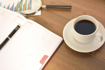 Financial documents, graphics, statistical calculations and a mug of coffee on a wooden background. Coffee time. 
