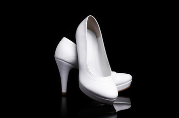 Pair Of White Classic Women's High-Heeled Shoes Isolated On A Black Background With Reflection