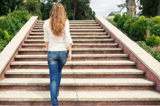 Rear View Of Young Woman Going Up The Stairs In The Park