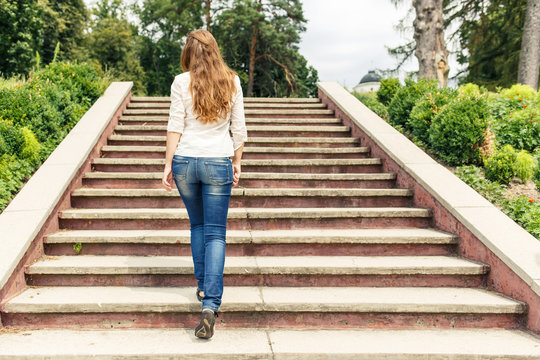 Rear view of young woman going up the stairs in the park