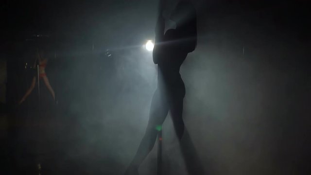 Silhouette of a girl on the pole in a smoke-filled room, slow motion.