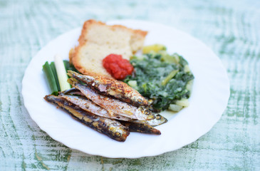 fried sprats with spinach and bread slices 