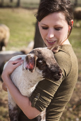 Frau hält kleines Lamm auf dem Arm, liebevoller Umgang mit Tieren