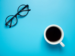 Flat lay photo of office desk with eyeglassesand cub of coffee on work table. Top view shot