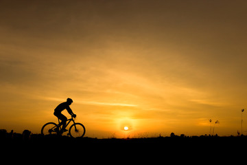 Silhouette of cycling on sunset background