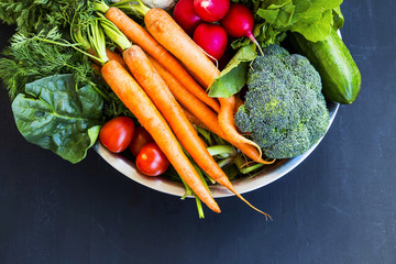 Fresh organic vegetables bowl with carrots, cauliflower, broccoli, tomatoes, mushrooms, radishes on wooden board