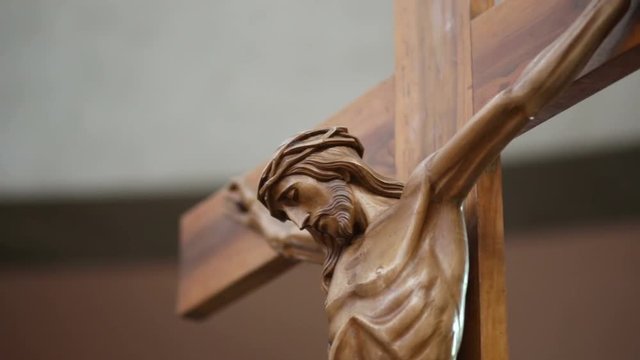 the camera horizontally moves from left to right framing a wooden statue of Jesus Christ on the Cross