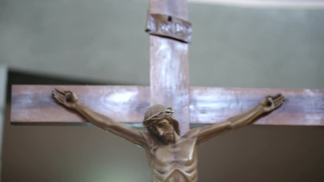 the camera horizontally moves from left to right framing a wooden statue of Jesus Christ on the Cross
