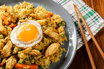 Fried rice nasi goreng with chicken egg and vegetables on a plat