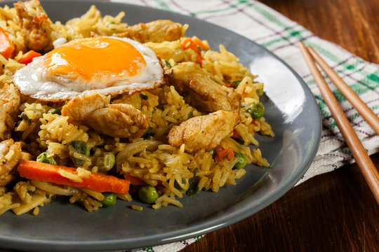 Fried rice nasi goreng with chicken egg and vegetables on a plate.