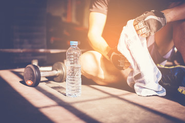 Muscular man at gym taking a break from workout sitting beside the bottle of water