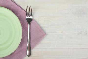 Green plate, fork and purple napkin