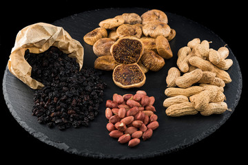 Dried figs, peanuts and black raisins on black dish