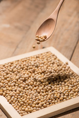 Soya beans in spoon on wooden table.