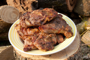 Juicy pork steaks cooked on an open flame grill on big white plate..