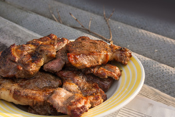 Juicy pork steaks cooked on an open flame grill on big white plate..