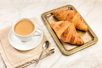 Cup of coffee with fresh croissants