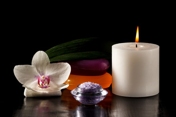 Fototapeta na wymiar Orchid flower, candle, soap and sea salt for spa procedures on black background