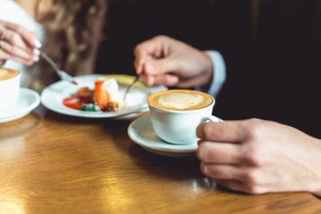 man's hand in a suit holding a cup of coffee