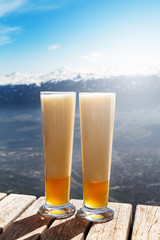 Tasty beautiful cold beer on a wooden table on mountain background. Beautiful landscape.