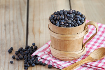Dried juniper berries in wooden cup. Copy space