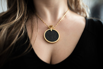 Chakra medallion hanging on the woman's neckline, made of alloy of many minerals, piece of meteorite and golden frame. © stockcrafter