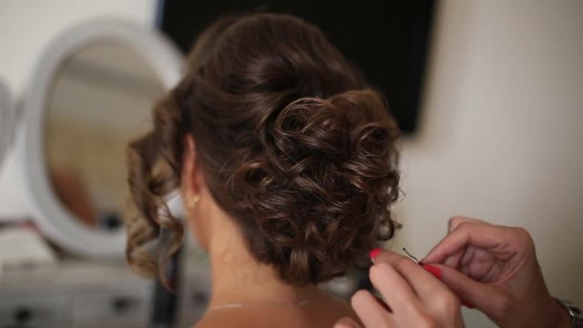The hairdresser does the bride's hair. Professional at work. The wedding image of the bride is a hairstyle.