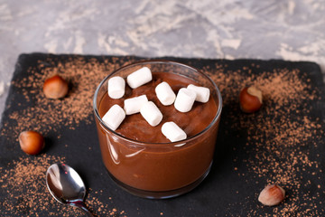 Chocolate mousse with marshmallows in portion glasses on slate cheese board