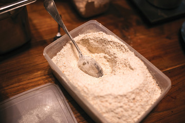 The plastic bowl with flour and small metal spoon