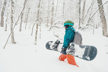 Freerider walking with snowboard in forest