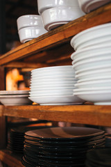 White plates and dishes on the wooden shelf on the kitchen