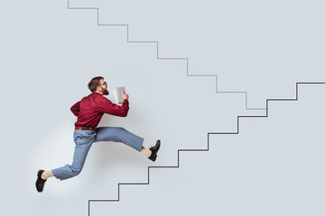 Young bearded man with books running up a drawn stairs