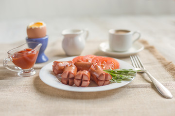 Breakfast - boiled egg, fried sausages, coffee cup and vegetables