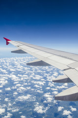 Wing of airplane flying above the clouds in the sky