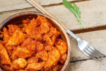 Chicken in tomato sauce in a wooden bowl.