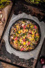 Italian pizza with black dough and seafood on a baking tray from the oven