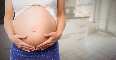 Pregnant woman mid section in blurry kitchen - obrazy, fototapety, plakaty