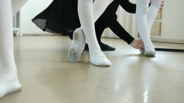 Group of a little ballerinas with teacher using ballet barre while practicing in dance studio. School of ballet