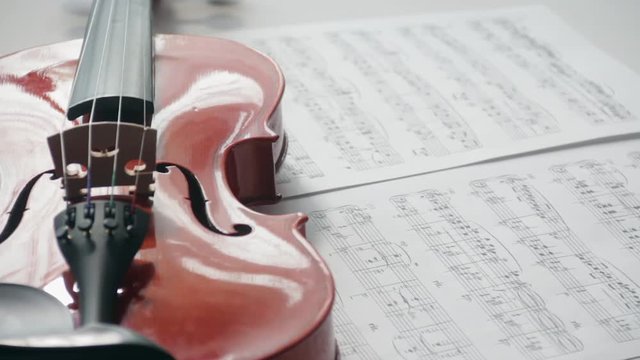 Brown violin with musical notes on a white background (spinning and panning footage). Presentation concept.