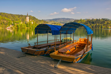 Naklejka na ściany i meble Wooden tourist boats moored to the pier on Bled lake, Slovenia