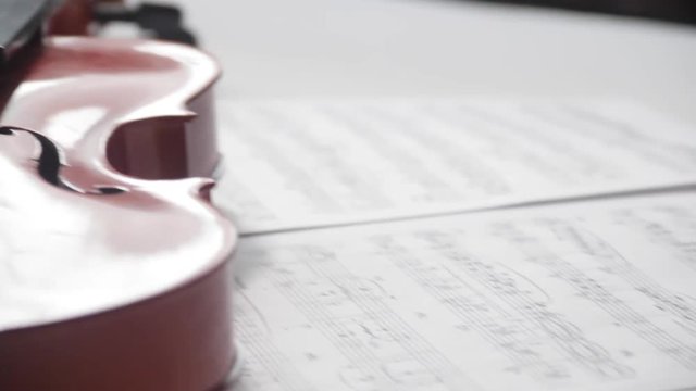 Brown violin with musical notes on a white background (spinning and panning footage). Presentation concept.