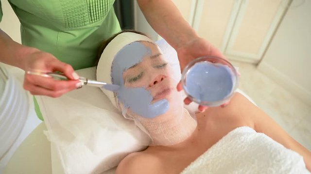 Young beautiful woman in a blue mask for the face. Spa treatment