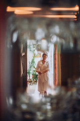 Obraz na płótnie Canvas Bride on silk robe looking on window with wedding dress at room on morning day.