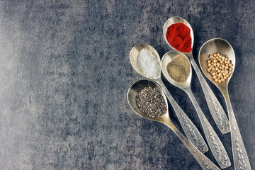 Spices in metal spoons on a dark background. Ingredients for cooking.