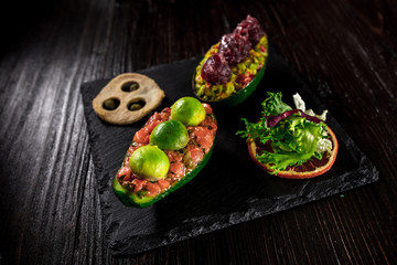 Fototapeta na wymiar Salmon tartare and avocado salad on a black background