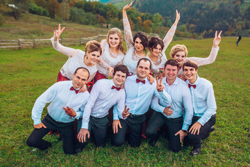 Groomsman and bridesmaids having fun and posing on camera behind beautiful mountains.
Wedding day. Without bride and groom.