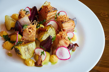 Baked potato slices and beets with vegetables and roast pork bacon