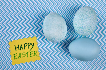 Dyed eggs on blue suraface. Happy Easter greeting card. Warm Easter congratulations.