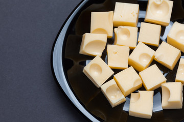 Yellow cheese cubes in a black plate
