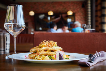 Baked cod fillet with vegetables in restaurant interior